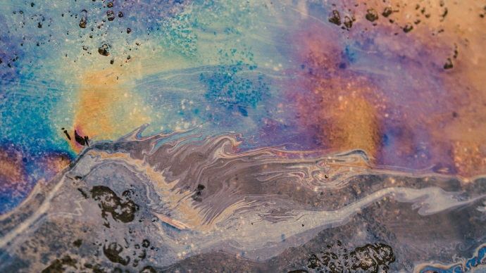Iridescent oil slick on water surface with colorful patterns